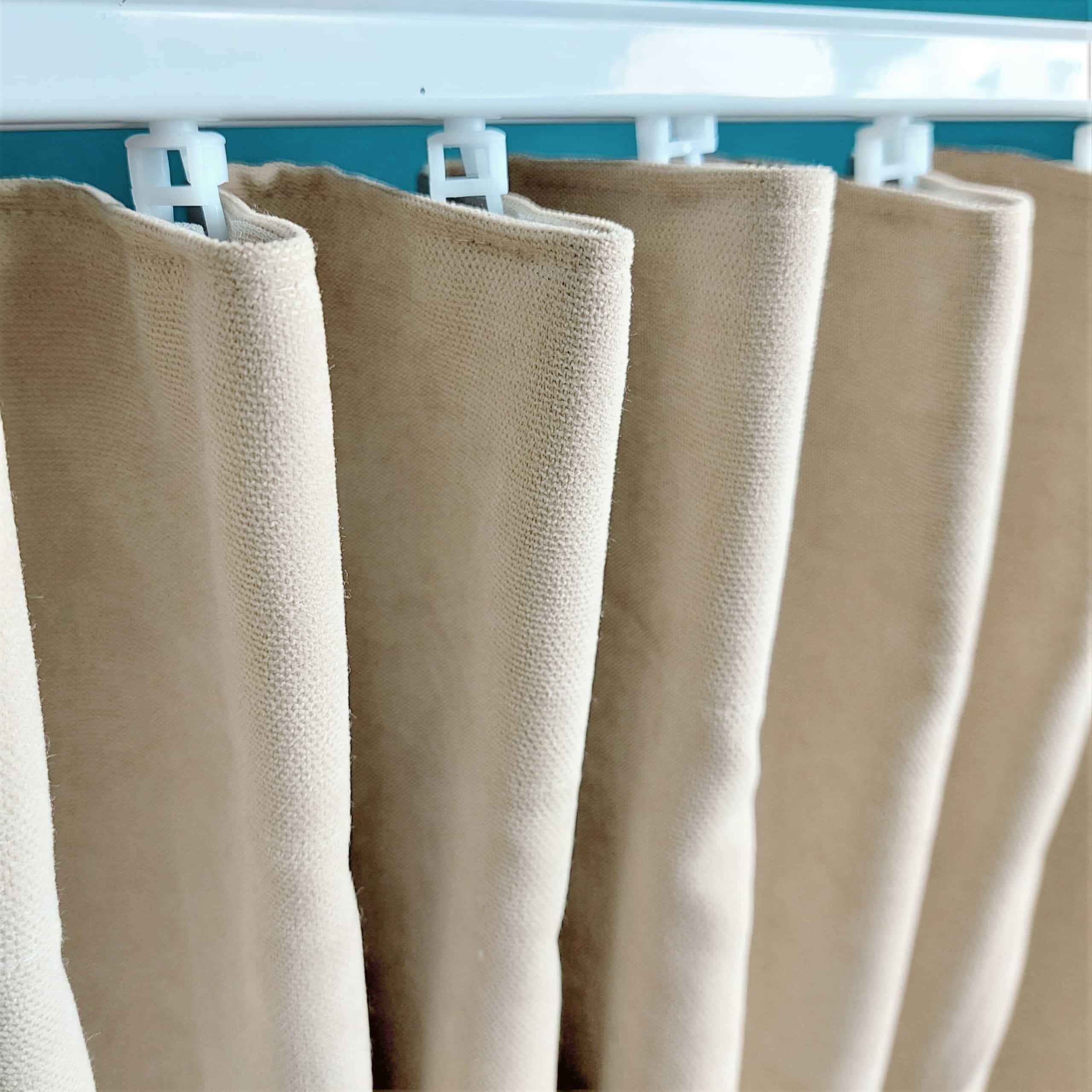 Beżowa zasłona zawieszona na karniszu, widok z bliska, gładka tkanina w domowej aranżacji wnętrz.