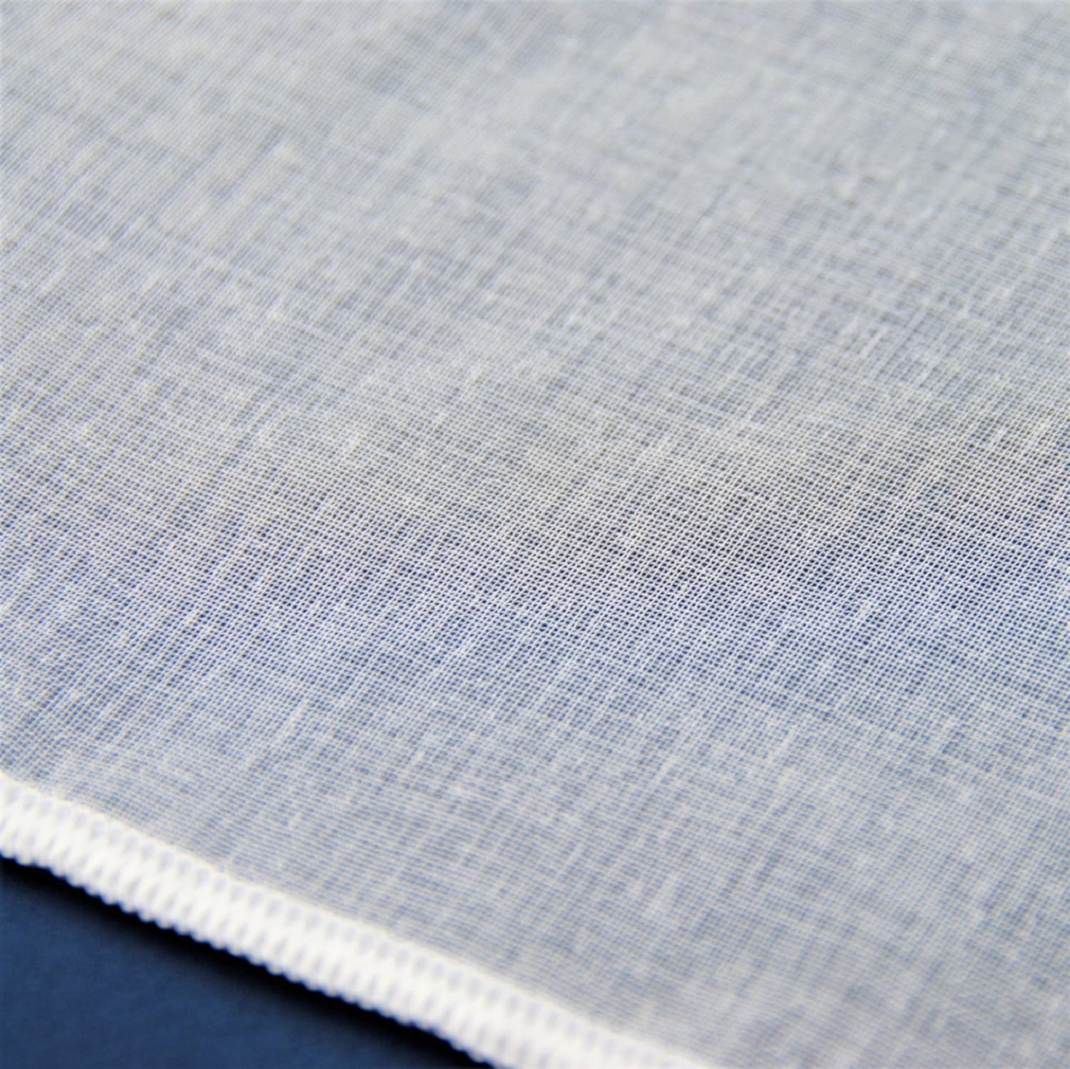 2154-2 Przezroczysta biała tkanina na ciemnym tle, zbliżenie tekstury materiału.