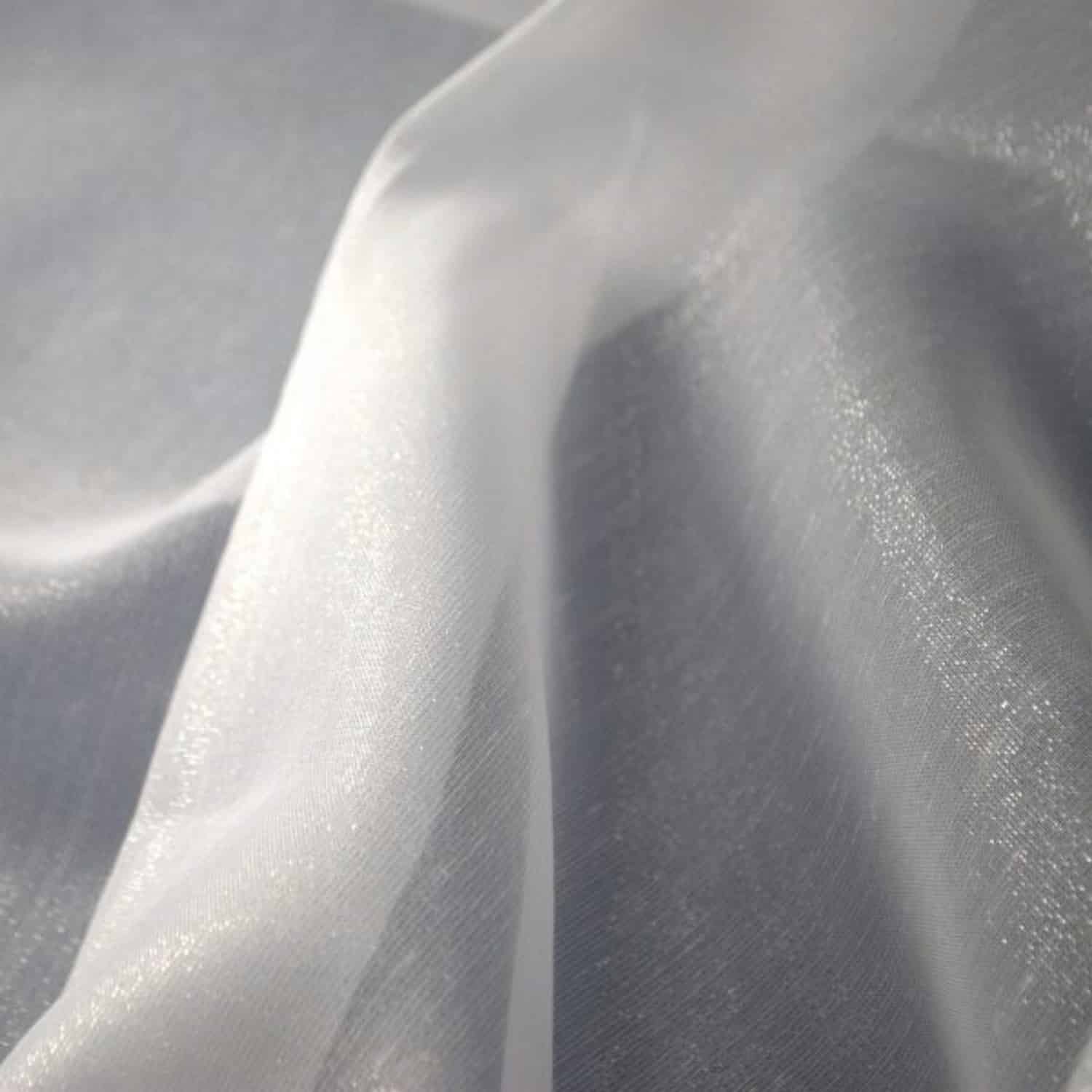 Przezroczysty materiał organza w świetle, delikatne fałdy i połysk na powierzchni tkaniny.