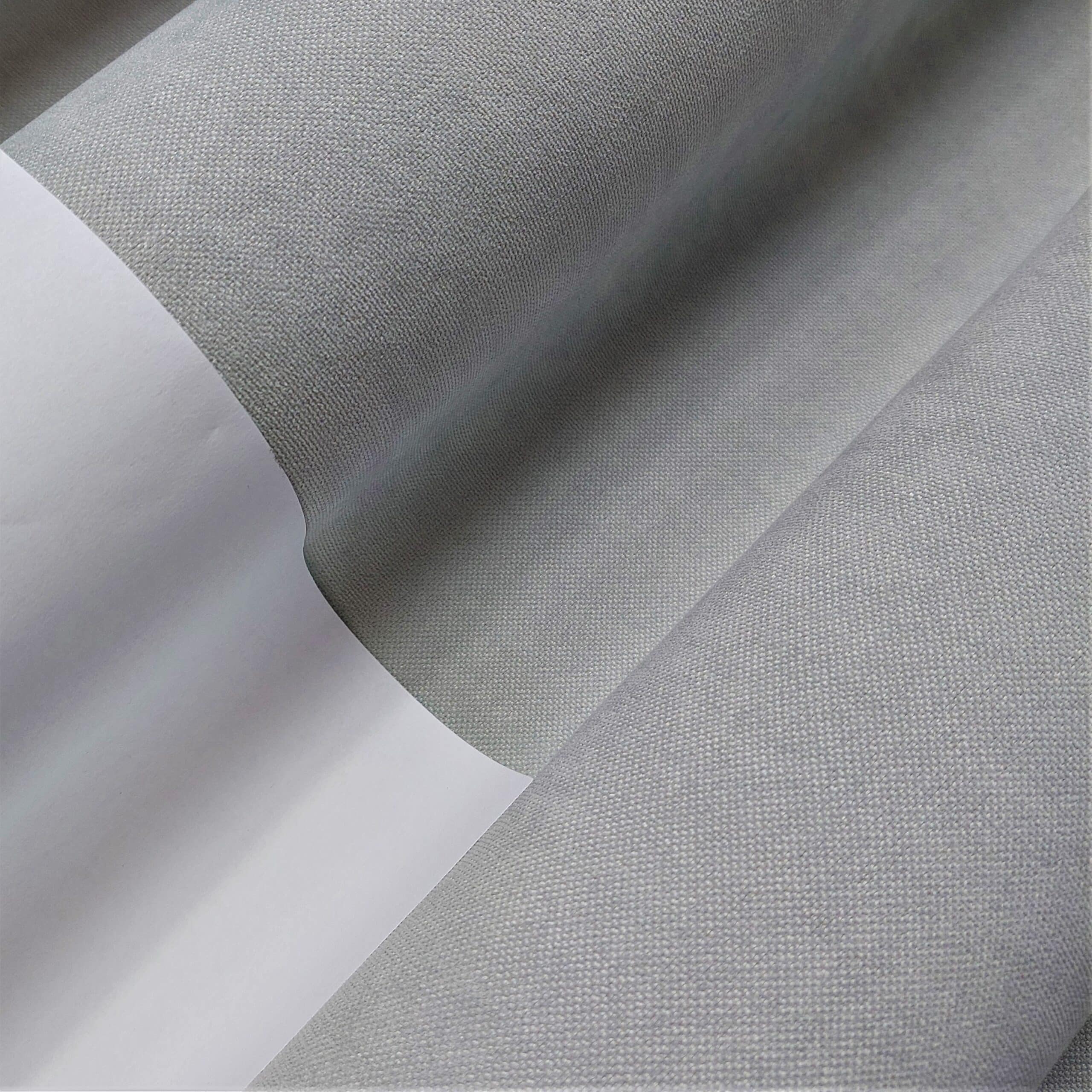 Zbliżenie na szary materiał w rolce, tekstura tkaniny i gładka powierzchnia widoczne na zdjęciu.