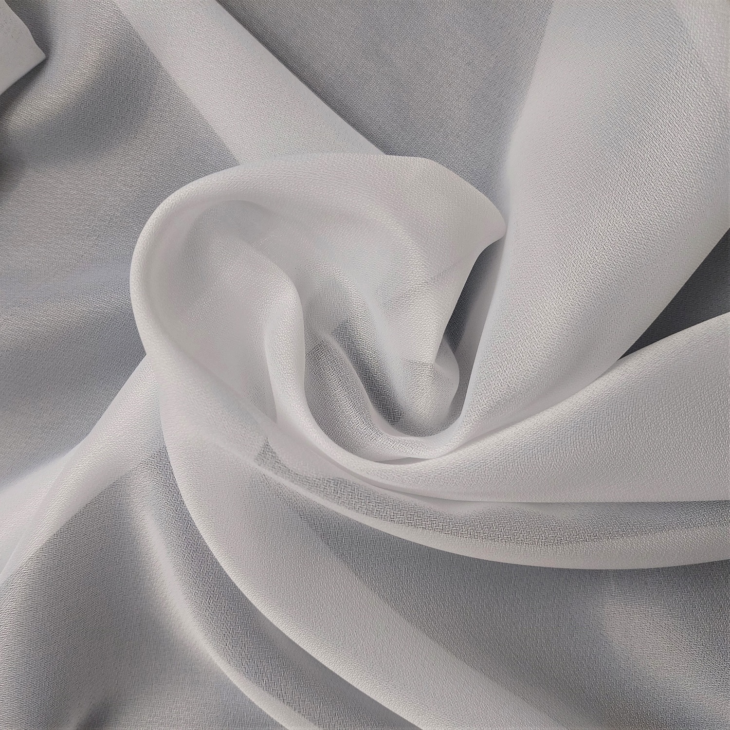 Białe, jedwabiste tkaniny ułożone w miękkie fale na szarym tle.