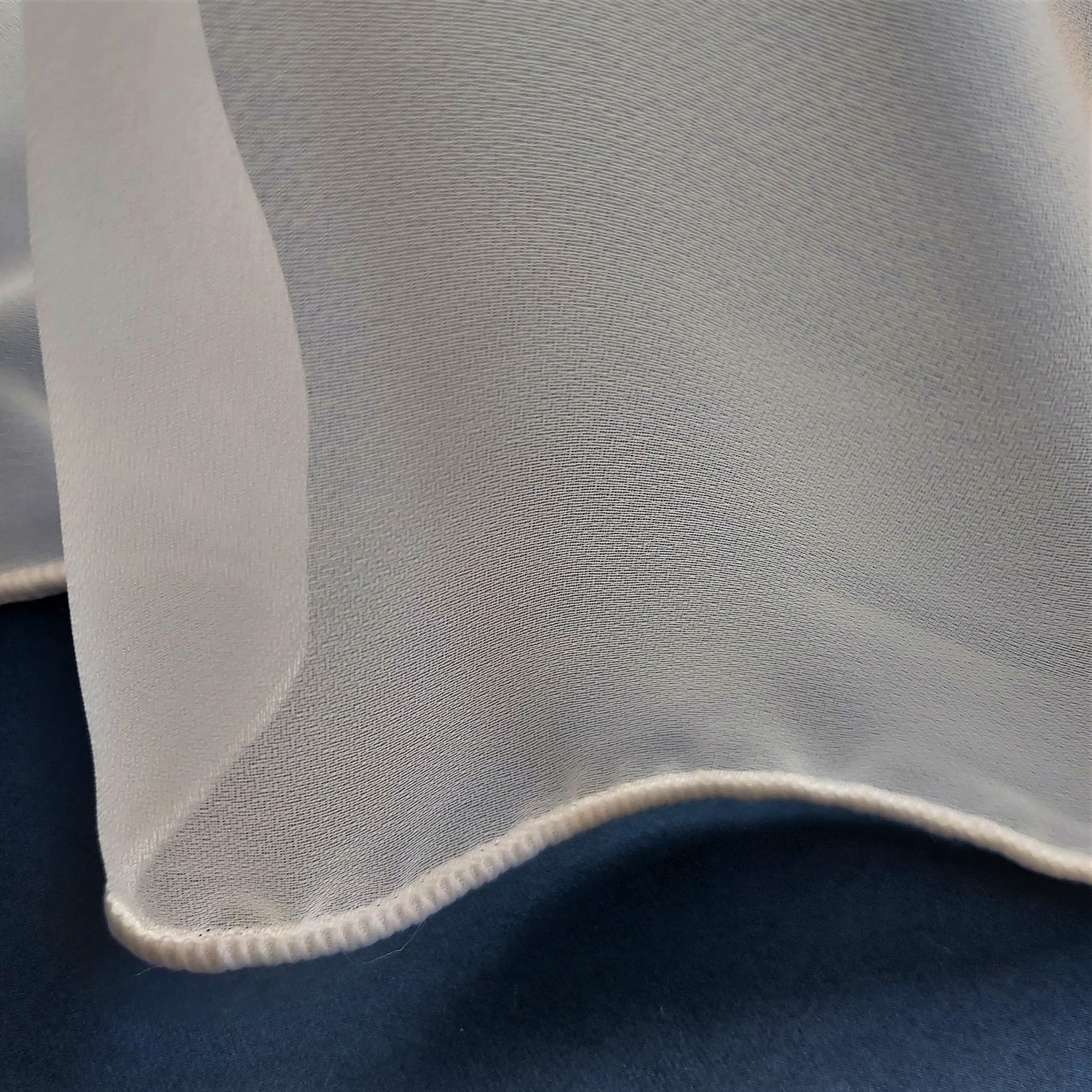 Przezroczysta tkanina na niebieskim tle, elegancki materiał o delikatnej fakturze.