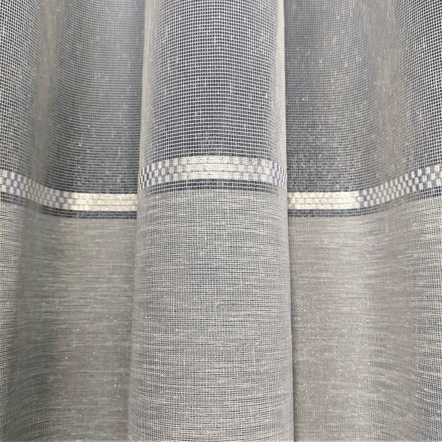 Szara zasłona z delikatnym wzorem kratki, wykonana z półprzezroczystego materiału, elegancko opadająca w fałdy.