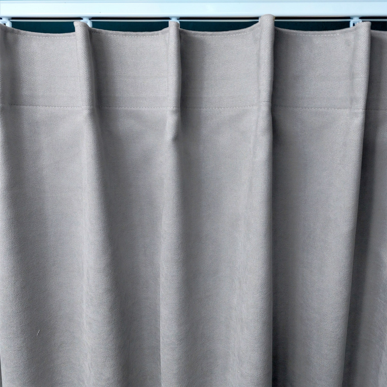 10843_marszczenie1_zmiana Szara zasłona z gładkiego materiału wisząca na karniszu, idealna do nowoczesnych wnętrz.