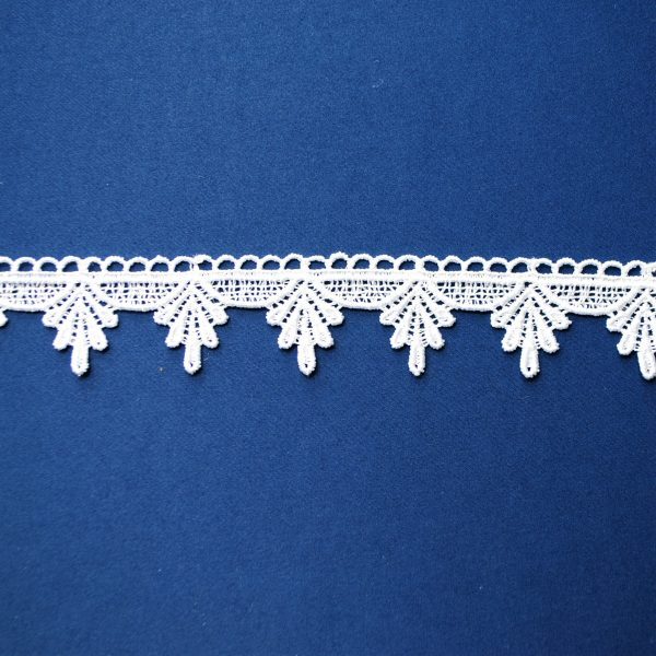 Koronkowa taśma biała na niebieskim tle, delikatny wzór z ząbkowanymi krawędziami.