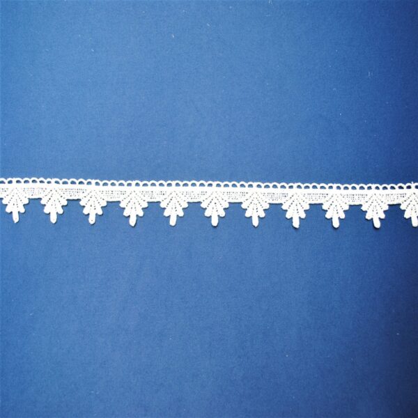 Biała koronka w delikatny wzór na niebieskim tle, idealna do dekoracji i rękodzieła.