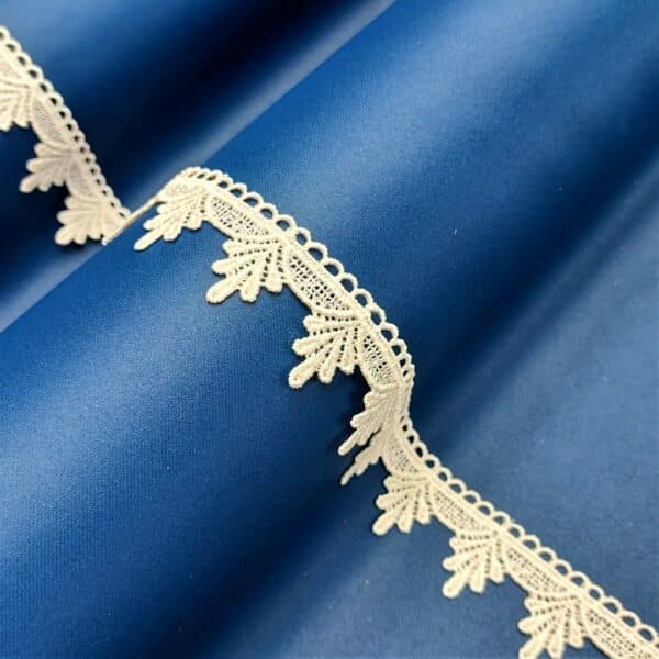 Niebieska tkanina z białą koronką w delikatny wzór, elegancki materiał dekoracyjny.