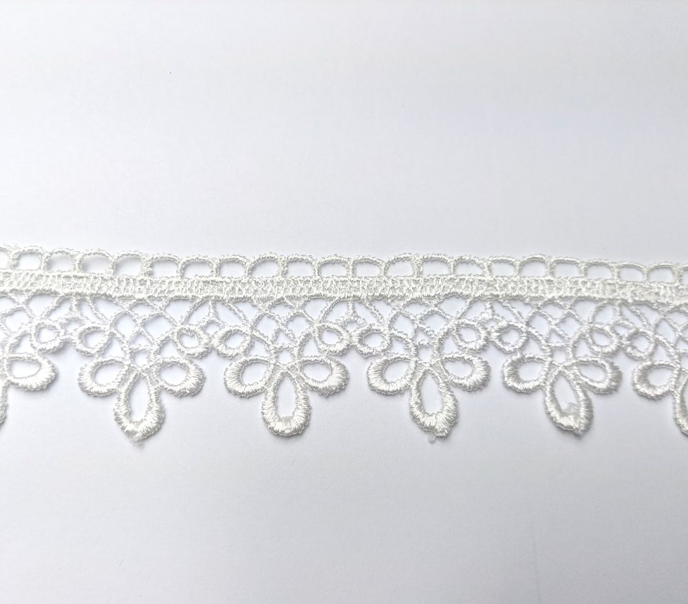 71528 a Koronka w kolorze białym na tle białej powierzchni, skomplikowany wzór kwiatowy.