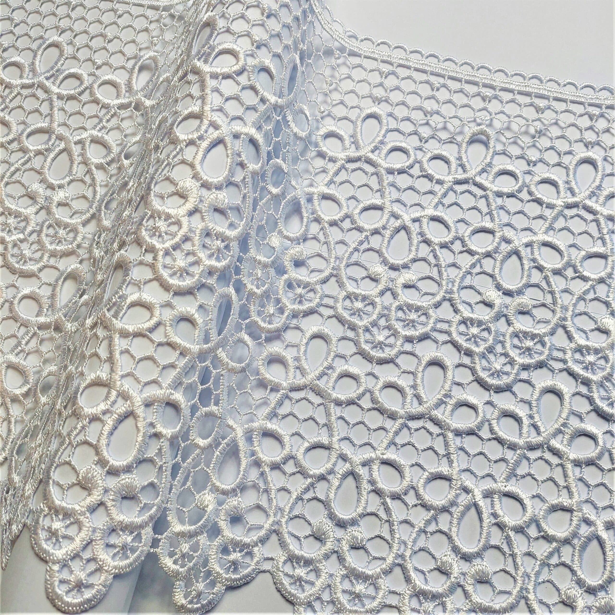 Biała koronka o delikatnym, ażurowym wzorze na tle neutralnym. Idealna do dekoracji i szycia odzieży.