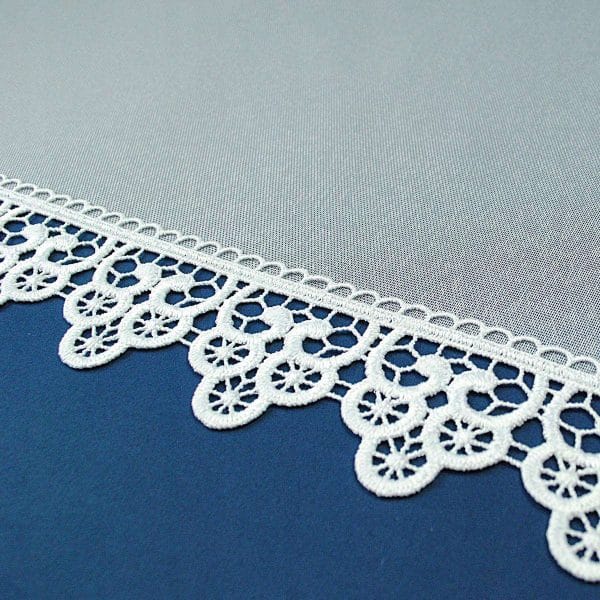 Biała koronka na niebieskim tle, dekoracyjny motyw, elegancki wzór.
