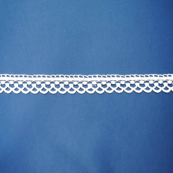 Biała koronka na niebieskim tle, delikatny wzór z geometrycznymi elementami.