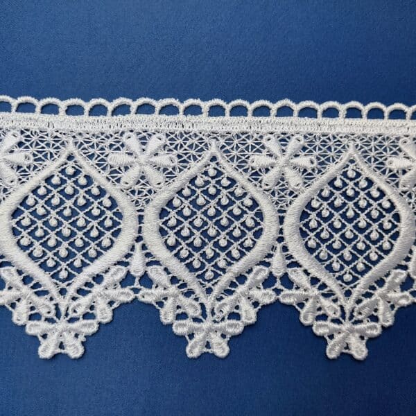 Biała koronka z delikatnym wzorem na niebieskim tle, elegancka i ozdobna, idealna na wykończenie tkanin.
