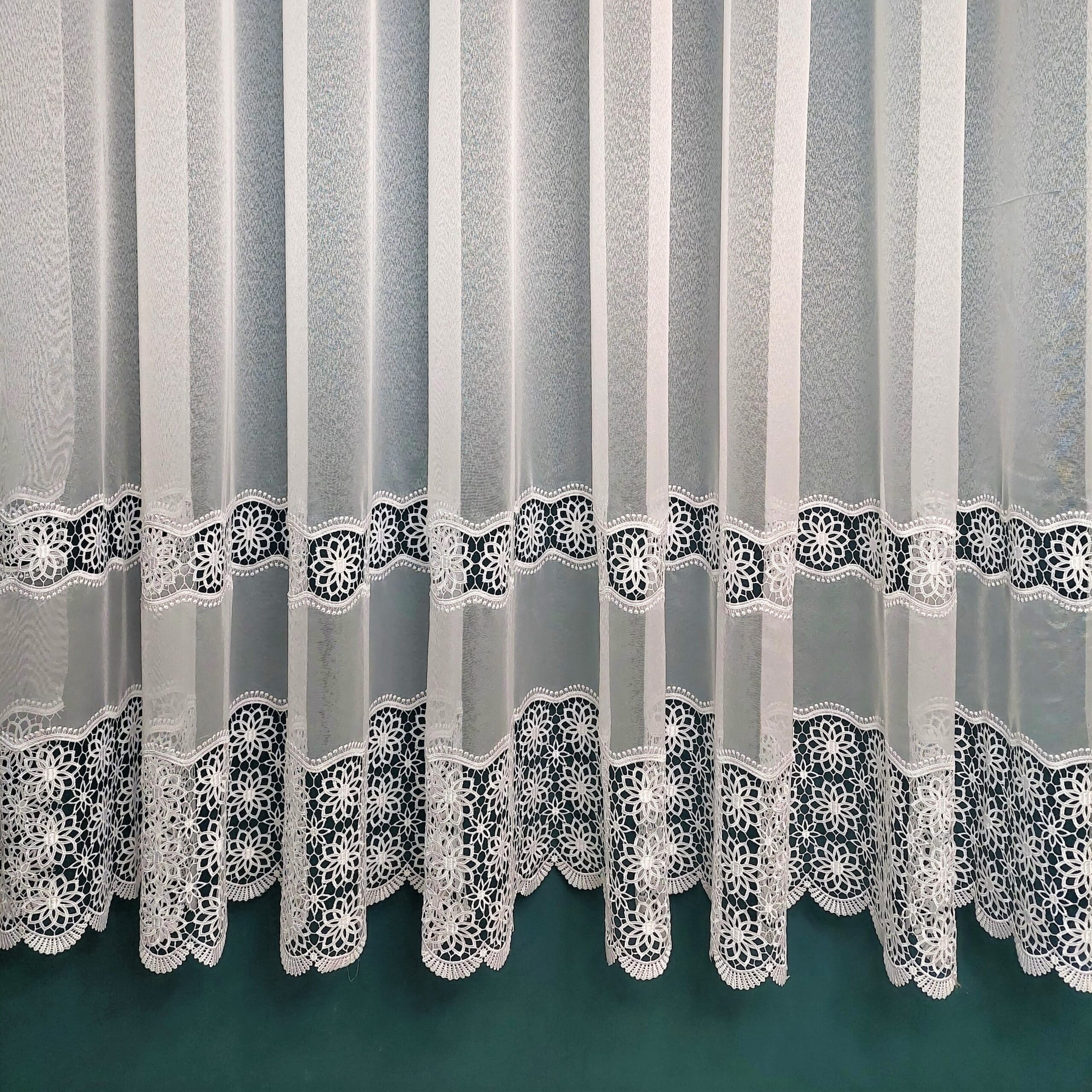Koronkowa zasłona w białym kolorze z dekoracyjnym wzorem kwiatowym, idealna do wnętrz eleganckich.