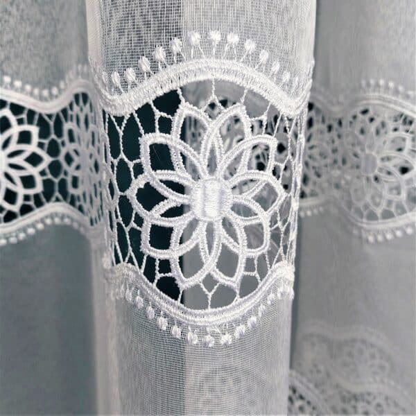 Koronkowa firanka zdobiona kwiatowym wzorem na przezroczystym tle, delikatna i elegancka dekoracja okienna.