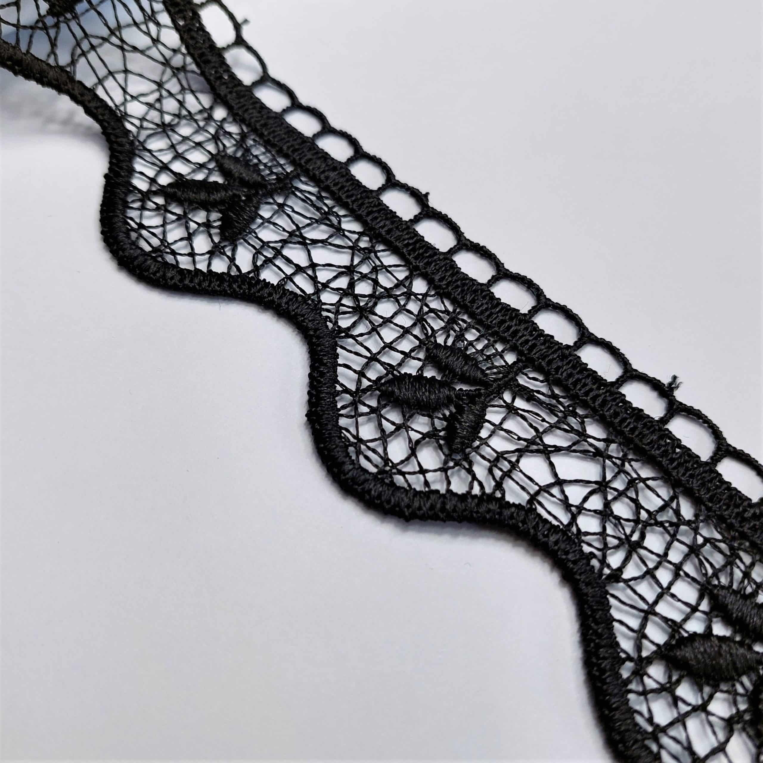 Czarna koronka na białym tle z misternym wzorem i falistym brzegiem, idealna do dekoracji lub mody.