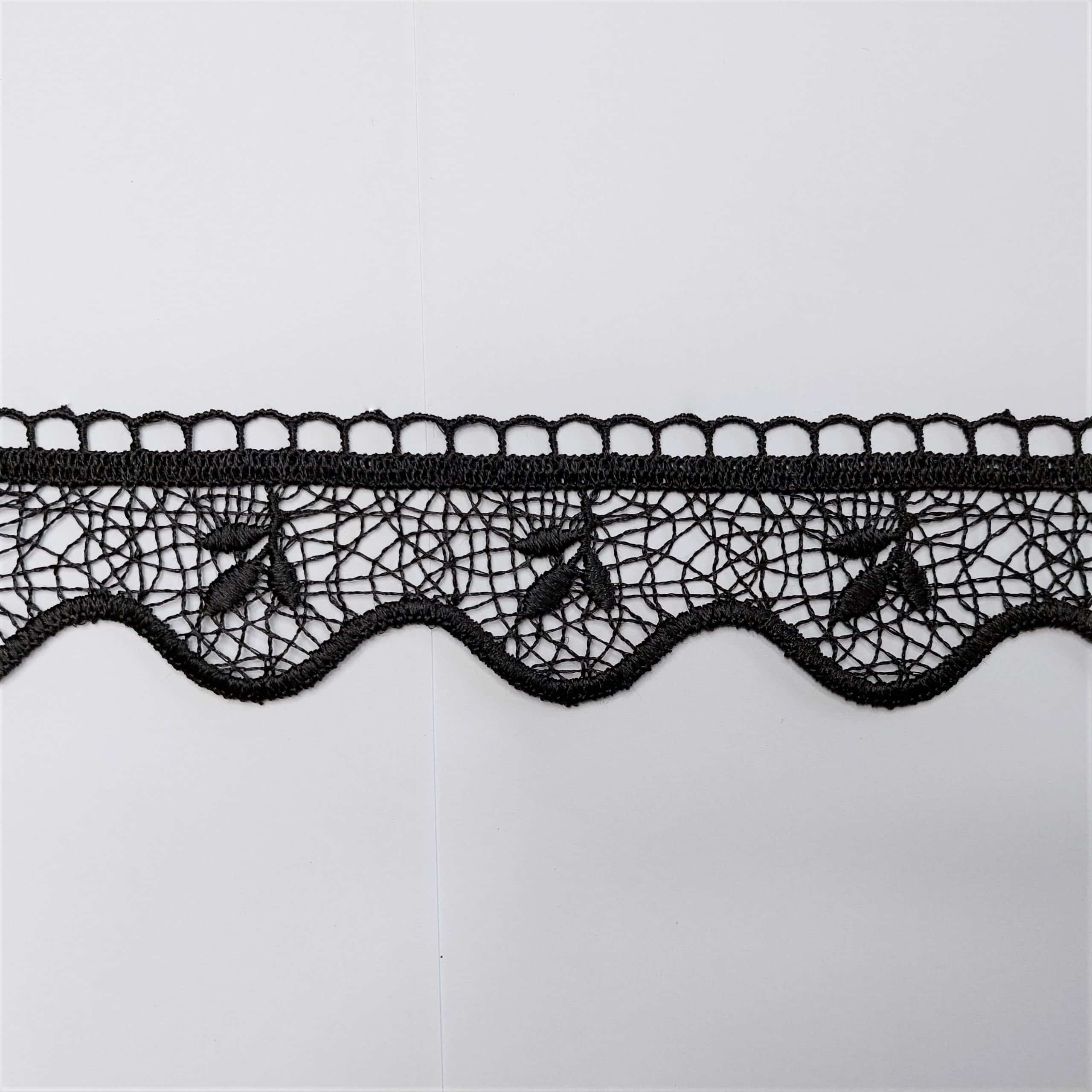 Czarna koronka z ozdobnym wzorem na białym tle.