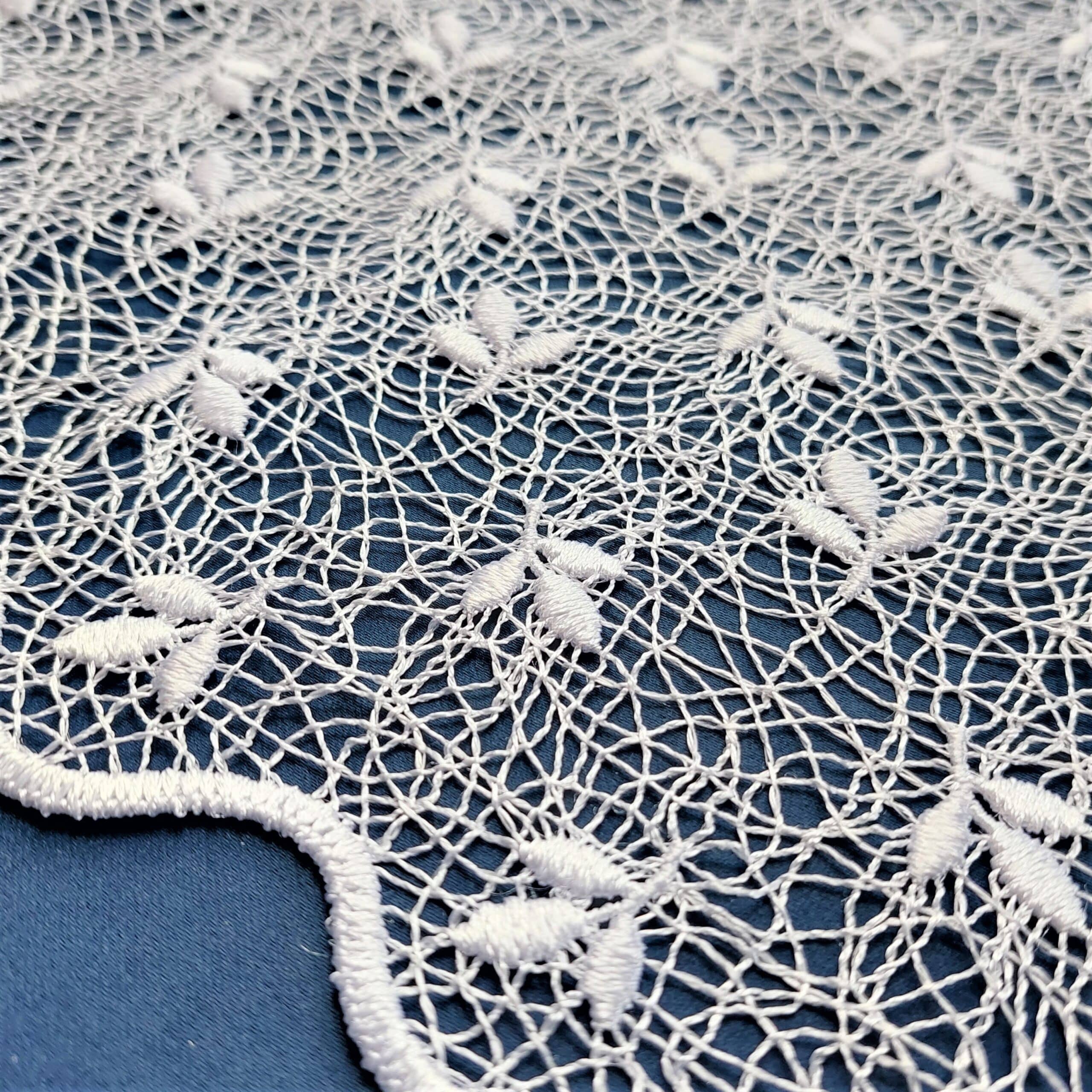 Koronkowy wzór na białym tle z delikatnymi haftowanymi detalami.