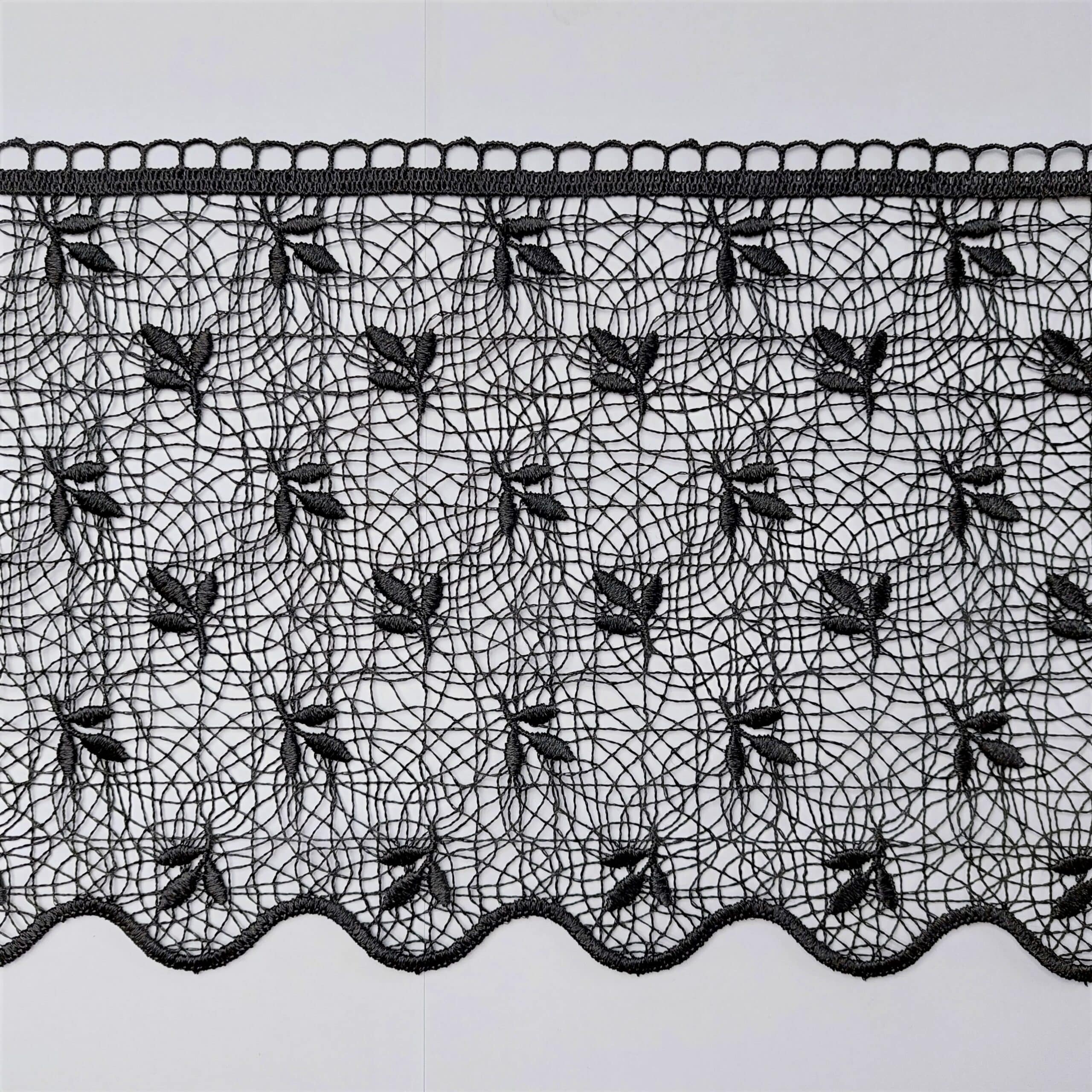 Czarna koronka z haftowanym wzorem liści na siateczkowym tle, elegancka i stylowa dekoracja tekstylna.