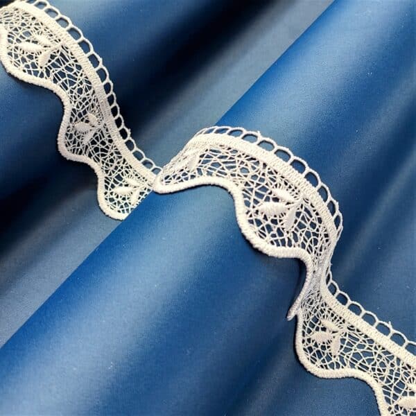 Niebieska tkanina z białą koronką, eleganckie zdobienie materiału.