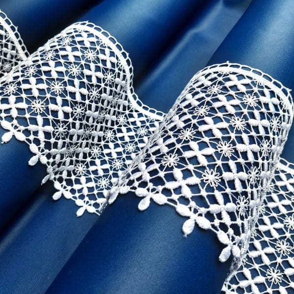 Białe koronkowe wzory na niebieskim tle, elegancki haft z delikatnymi kwiatami.