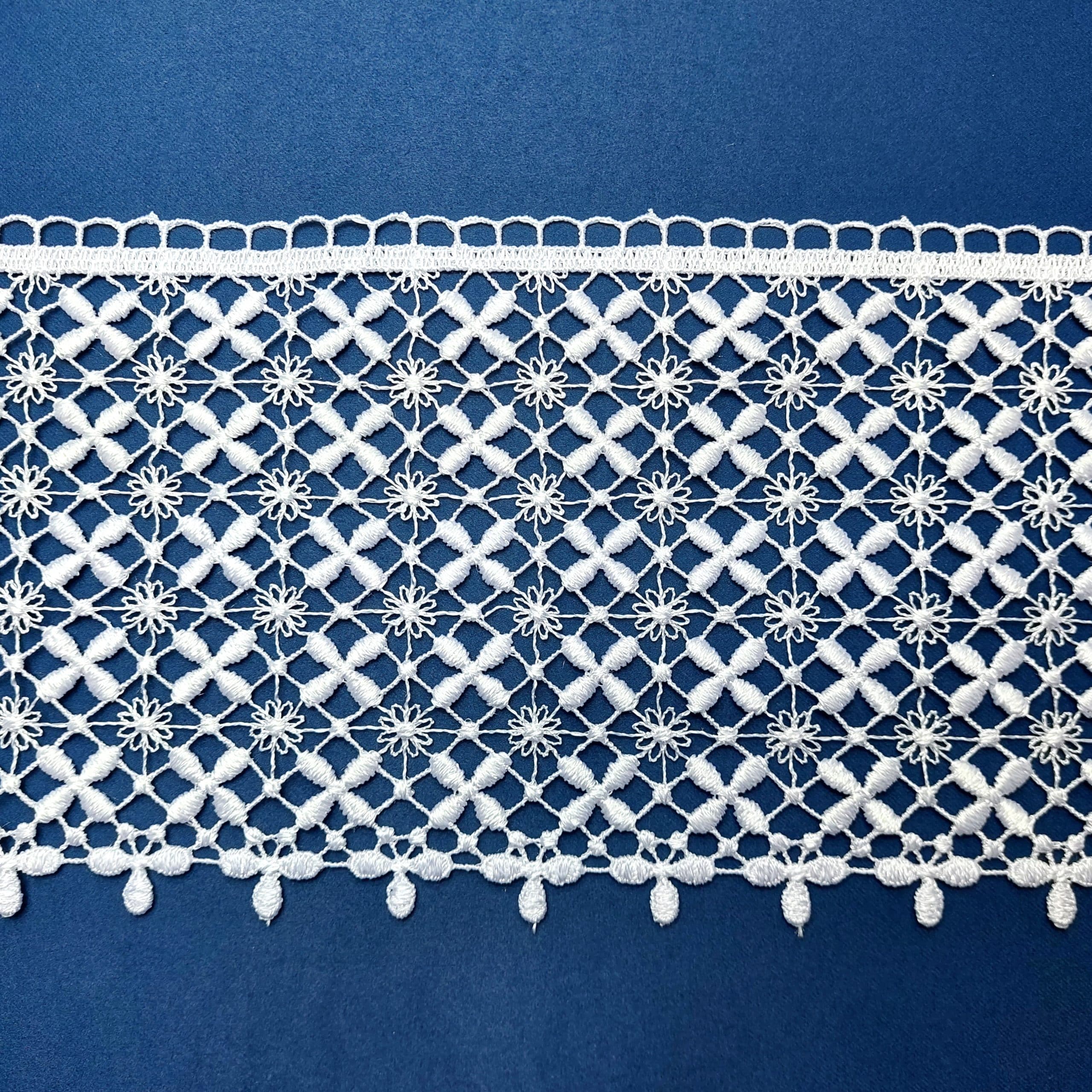 82690-15-3 Biała koronka na niebieskim tle o skomplikowanym wzorze z motywami kwiatowymi, idealna do dekoracji.