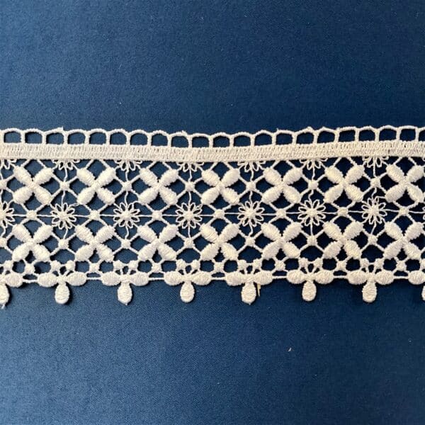 Koronkowa tasiemka z misternym wzorem kwiatowym na niebieskim tle. Eleganckie rękodzieło do dekoracji i szycia.