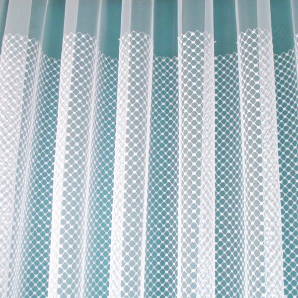 Przezroczyste firanki z wzorem kratki, wiszące na karniszu w jasnym wnętrzu.
