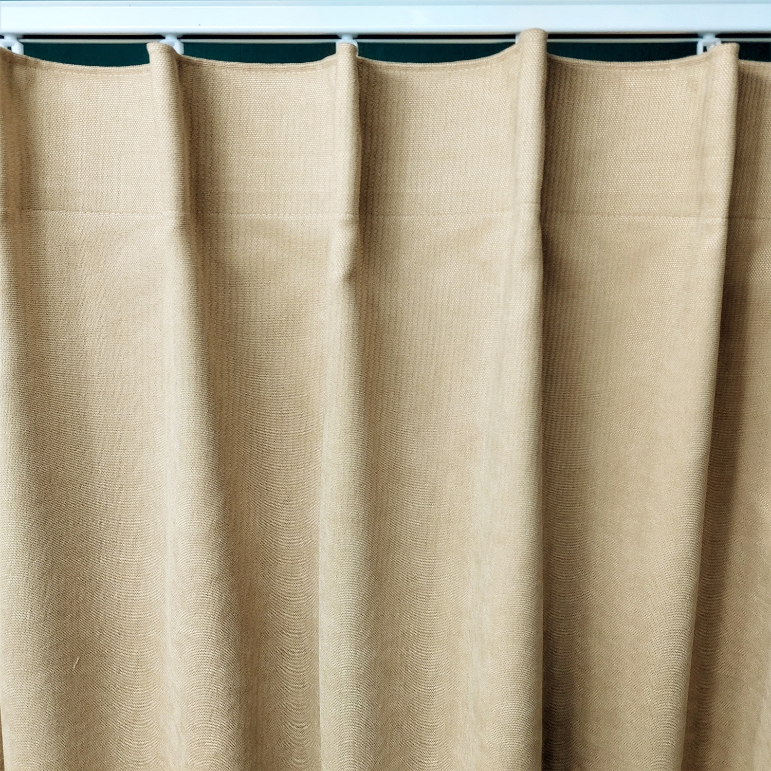 Marszczenie 1 10847_zmiana Beżowa zasłona z grubego materiału, elegancko upięta na białym karniszu, w domowym wnętrzu.