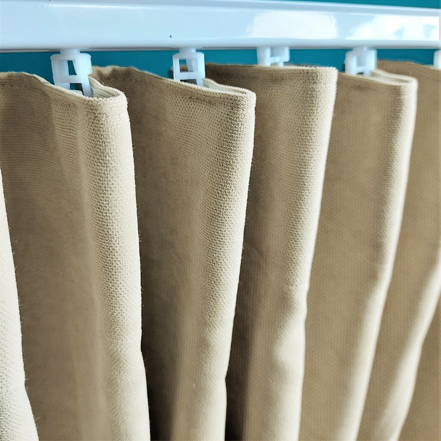 Marszczenie 3 10847_zmiana Białe klipsy trzymające beżowe zasłony na niebieskim tle.