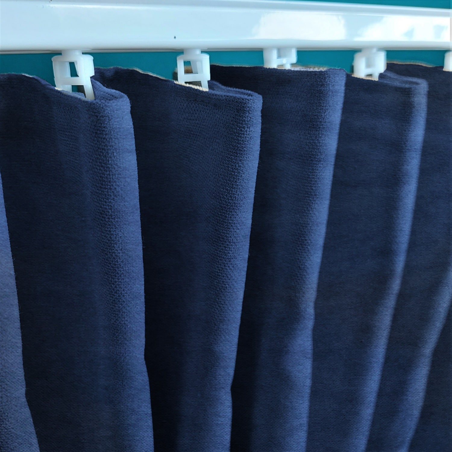 Marszczenie 3 12665_zmiana Ciemnoniebieskie zasłony wiszące na białym karniszu, widok zbliżony na materiał.