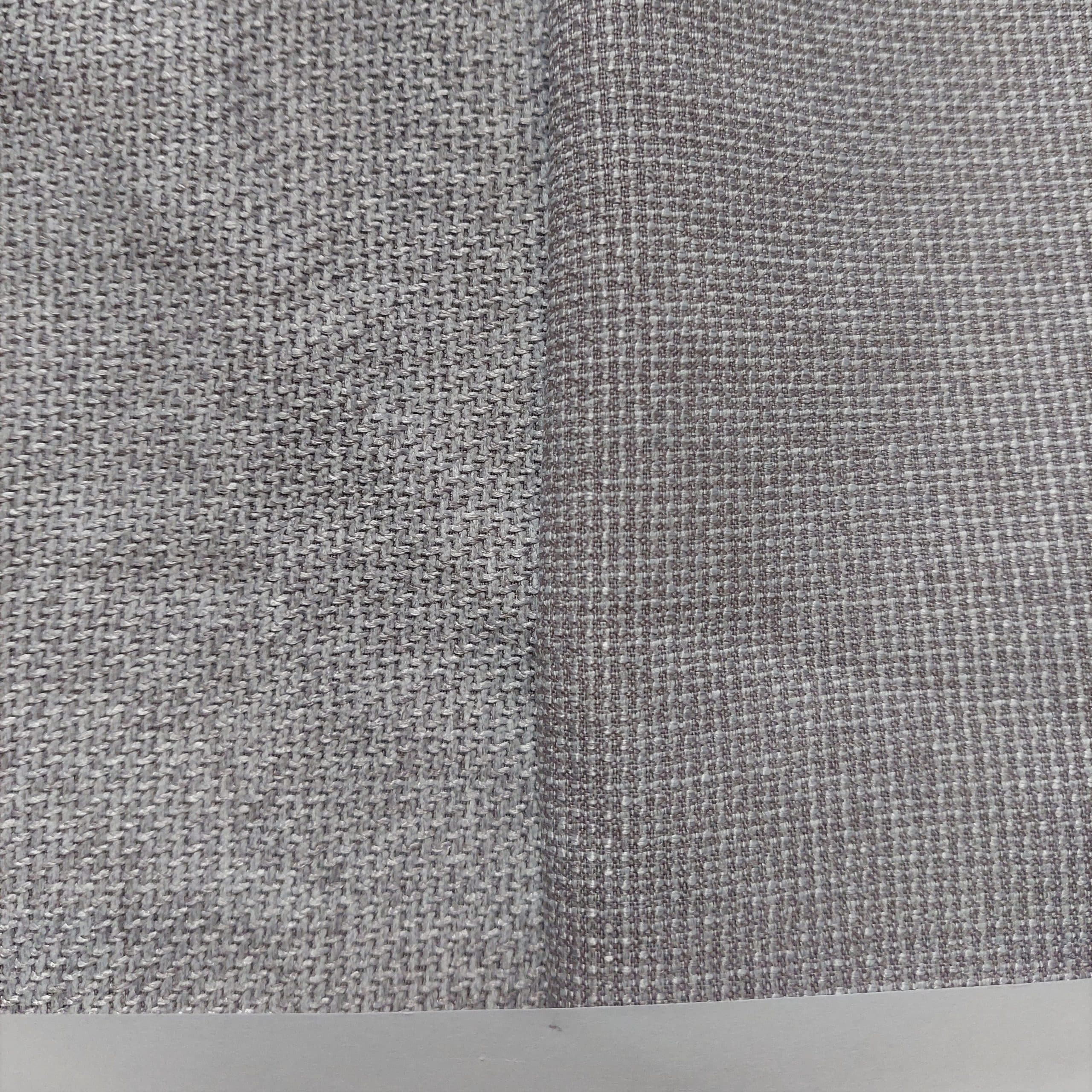Zbliżenie na fakturę szarej tkaniny z różnymi wzorami splotu po lewej i prawej stronie.