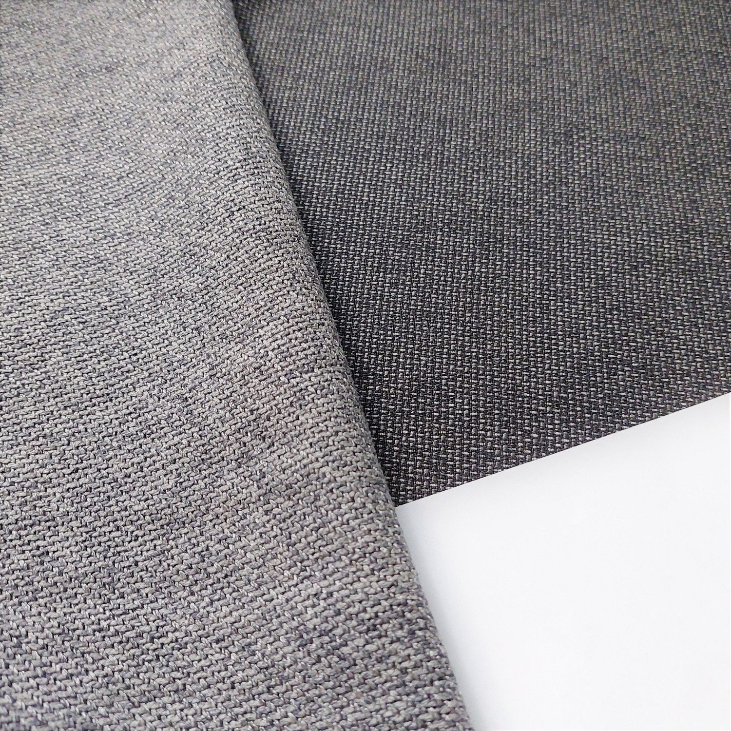 Dwa kawałki szarej tkaniny o różnej fakturze na białym tle, zbliżenie na detale splotu.