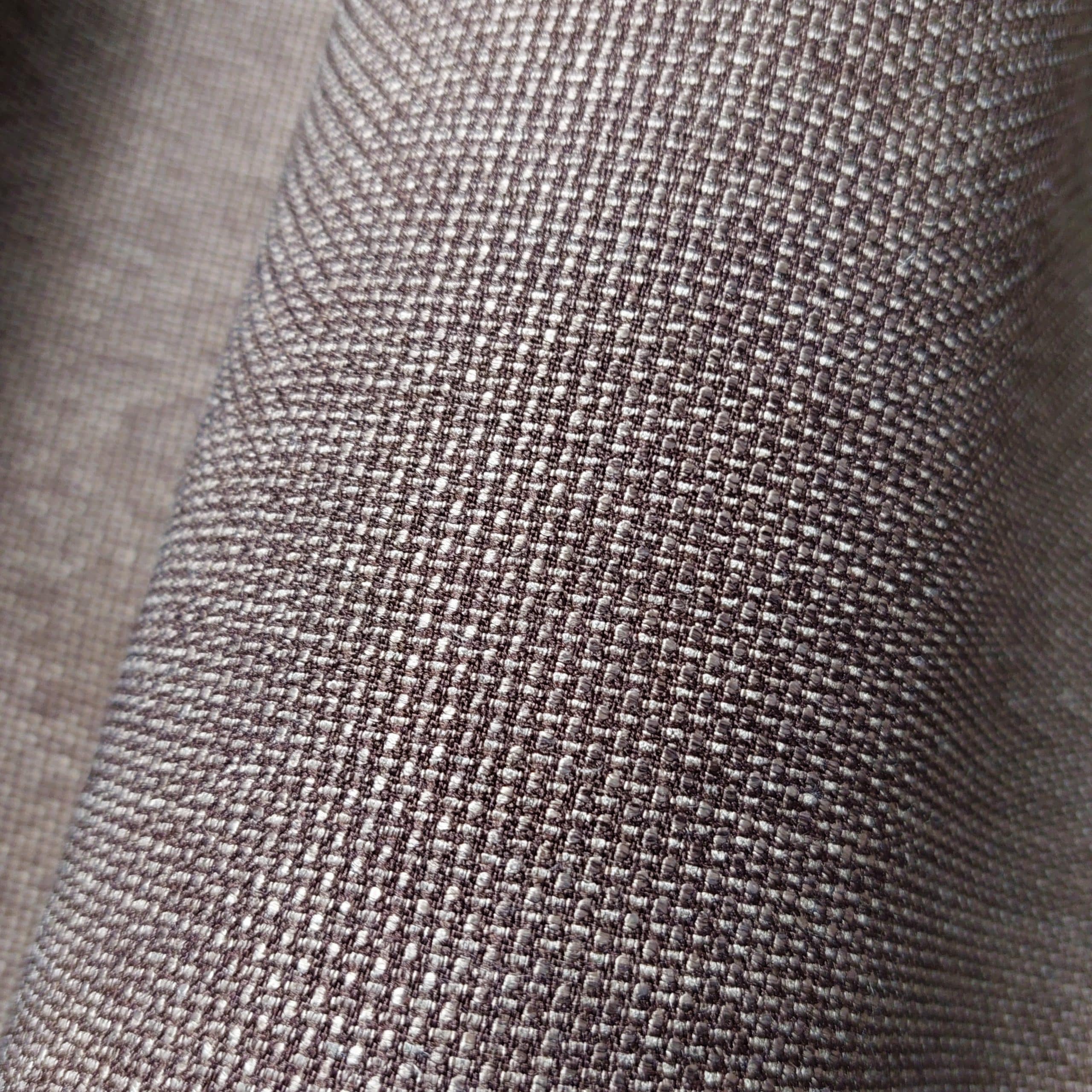 Zbliżenie na tkaninę o szarej teksturze z drobnymi splotami, idealną do wnętrzarskich projektów.