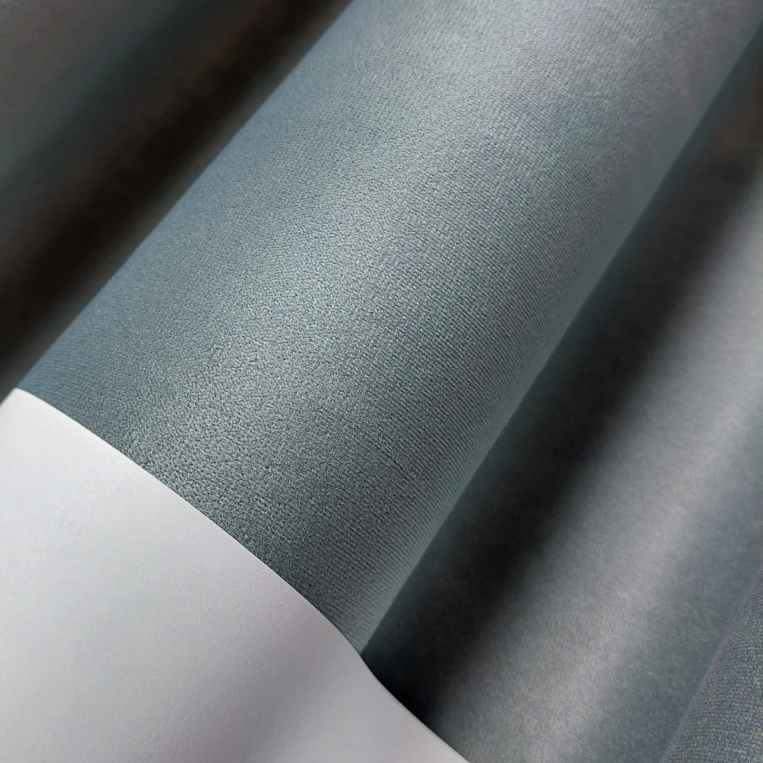 Szare, teksturowane rolki materiału na białym tle, ułożone w równoległych pasach.