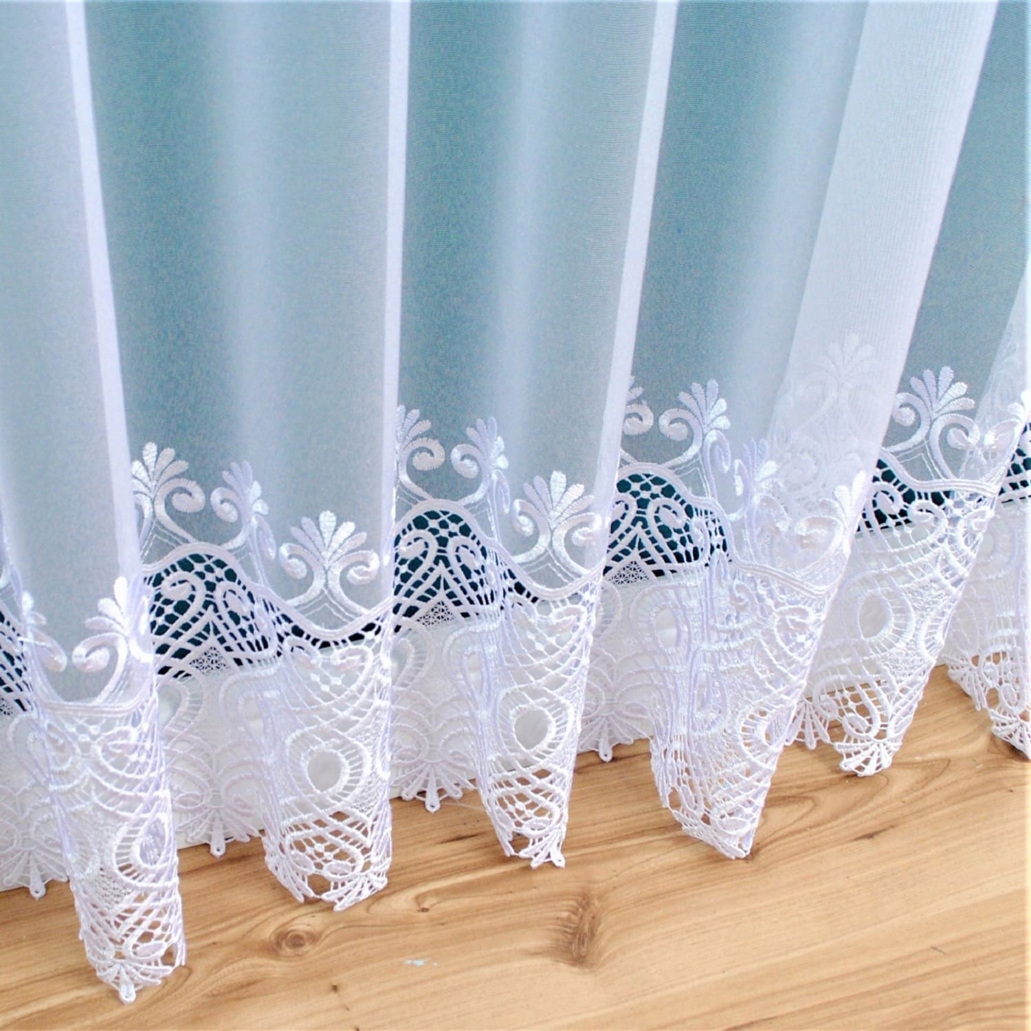 Biała koronka zasłony na drewnianej podłodze, elegancki wzór, delikatny styl dekoracji wnętrz.