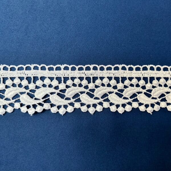 Koronkowa taśma na granatowym tle, ozdobna i delikatna, idealna do projektów krawieckich i dekoracji.