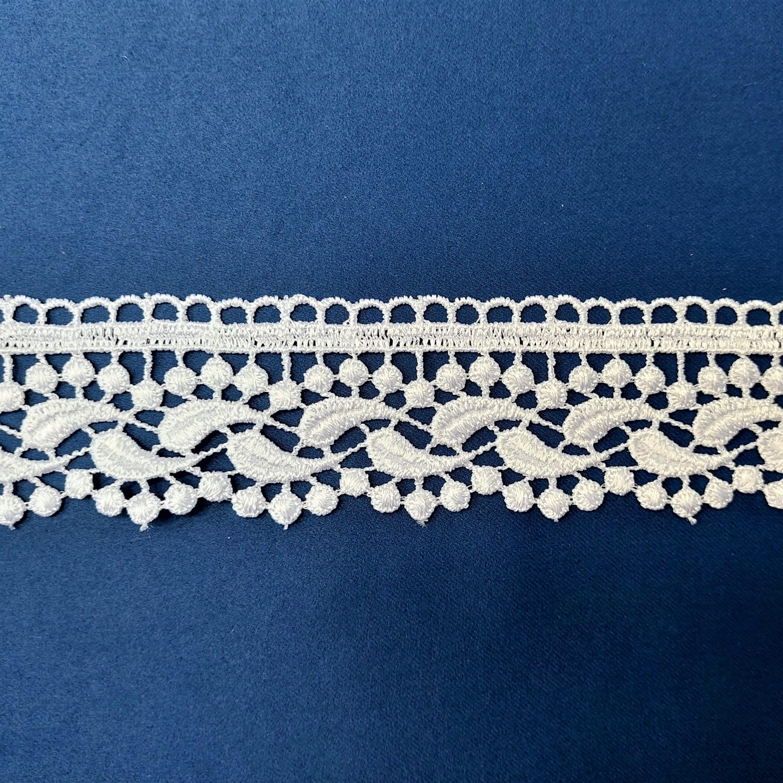 Koronkowa taśma na granatowym tle, ozdobna i delikatna, idealna do projektów krawieckich i dekoracji.