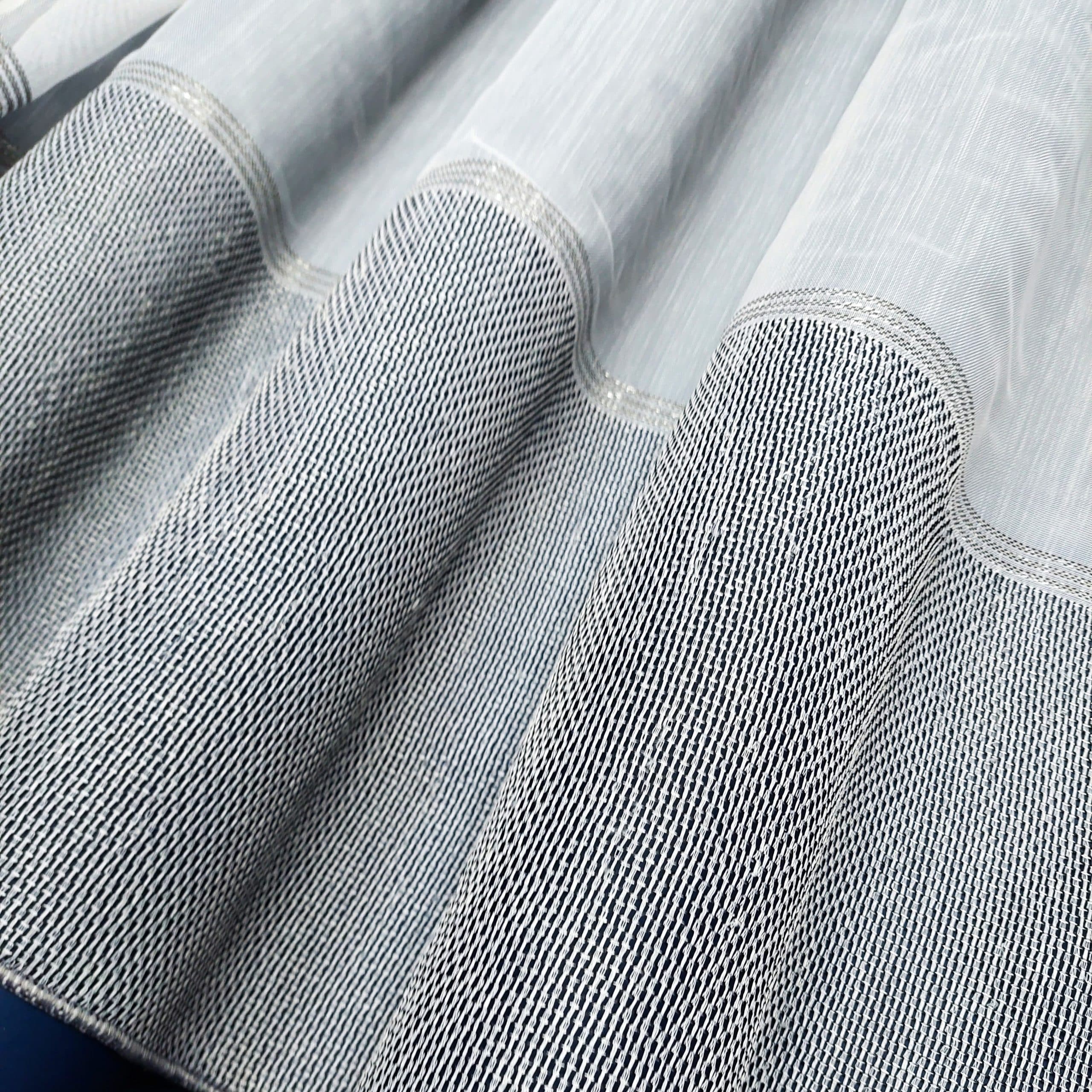 Bliska perspektywa nowoczesnej zasłony z jasnoszarego materiału o delikatnym wzorze do eleganckiego wnętrza.