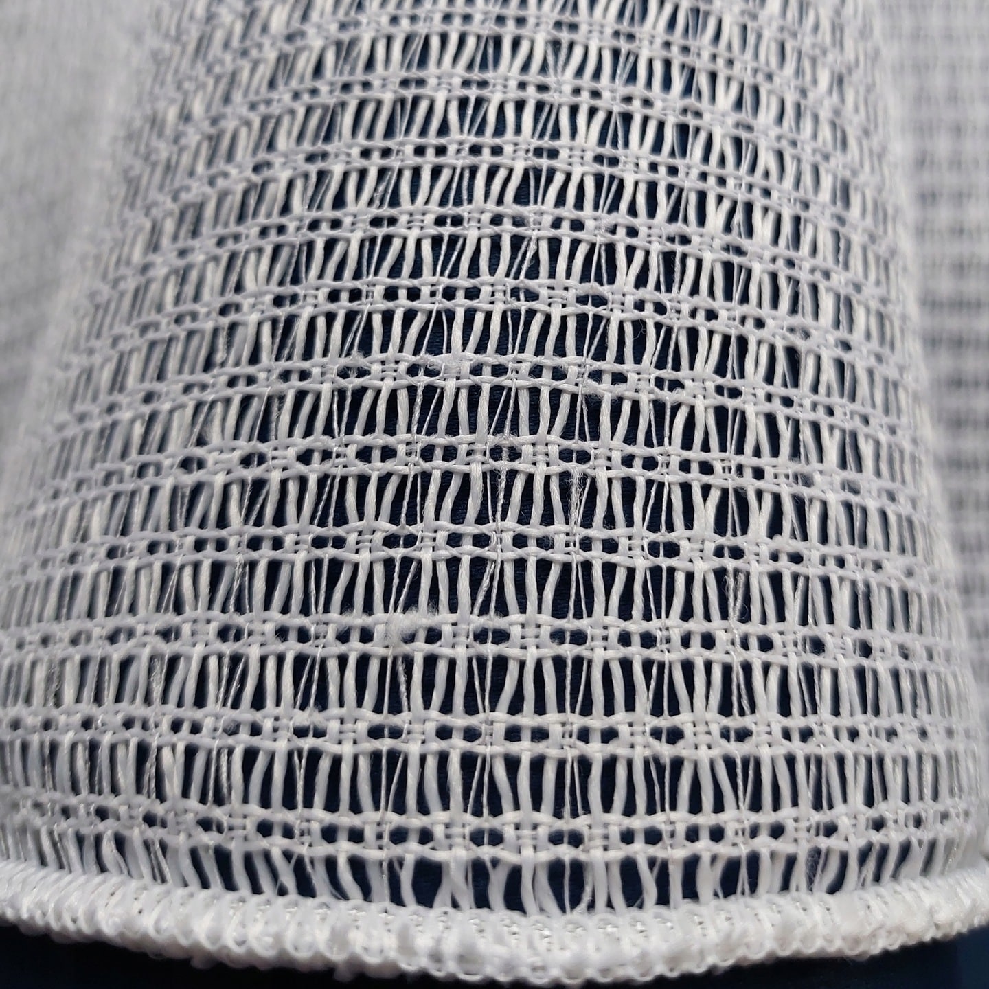 Biały materiał o strukturze siatki z bogatym wzorem tkaniny. Idealny do dekoracji i projektowania wnętrz.