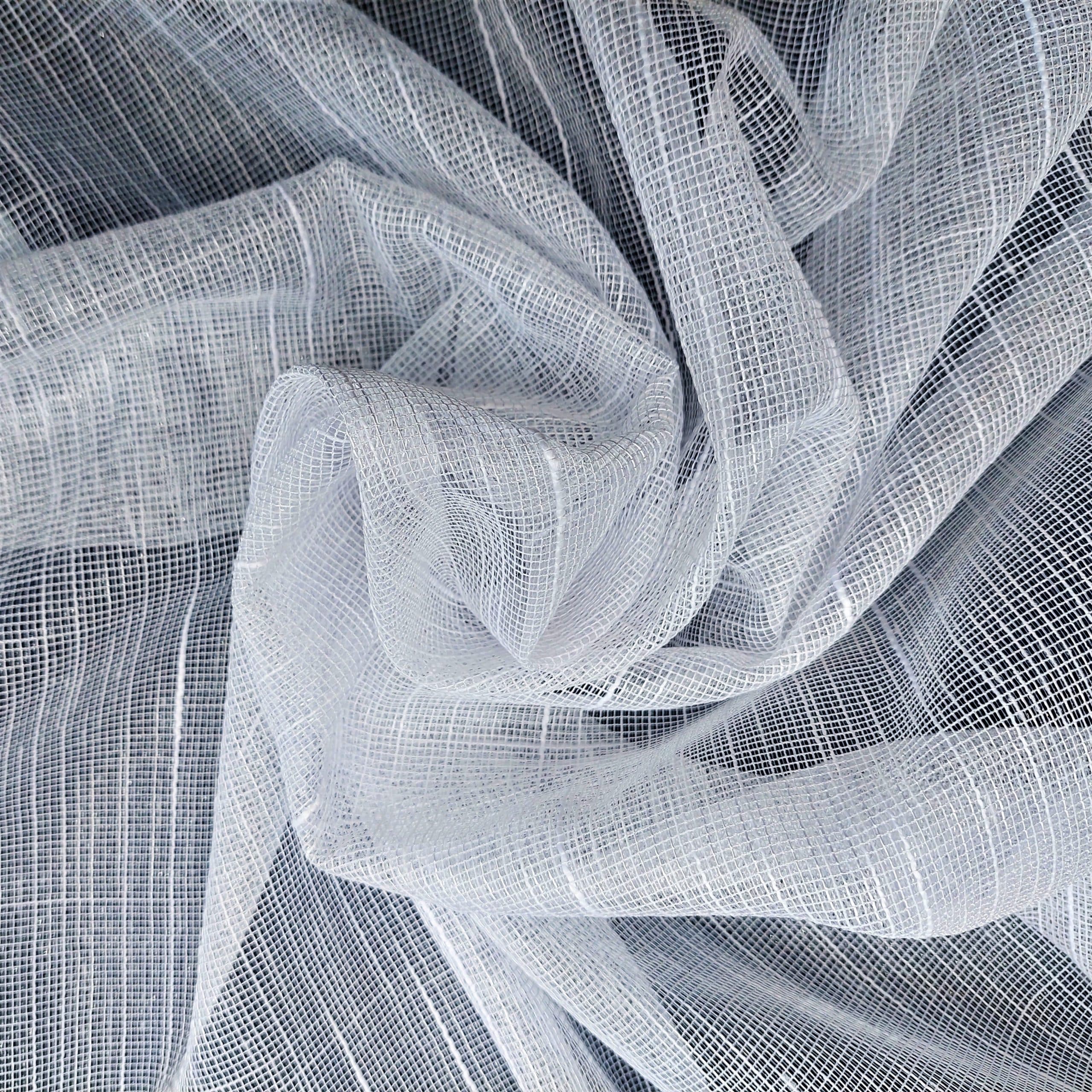 Biały, przezroczysty materiał o delikatnej siatkowatej strukturze, ułożony w artystyczne fałdy.