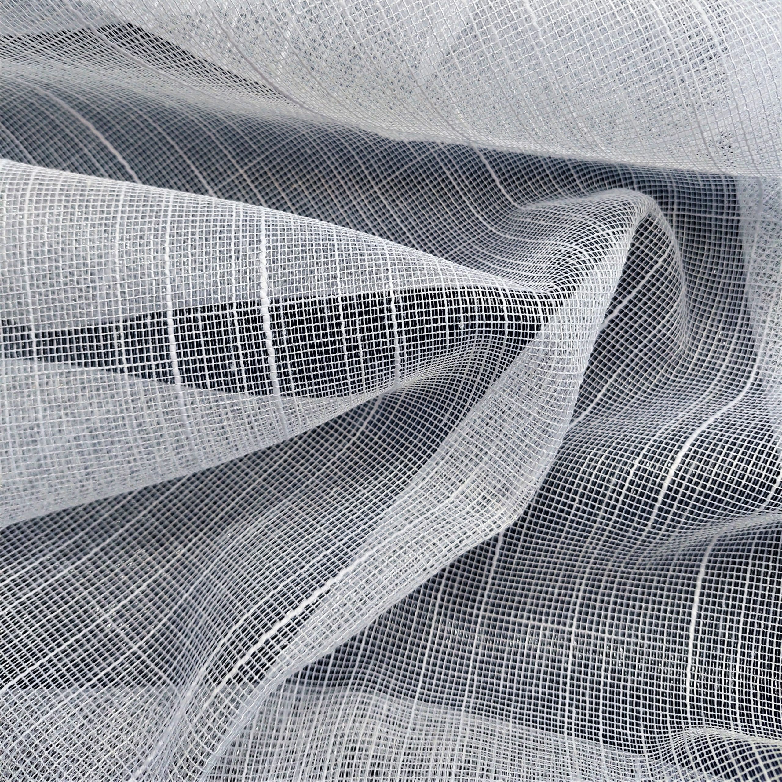 Przezroczysta biała tkanina z delikatnym, siatkowym wzorem na falistej powierzchni, tworząca efekt lekkości i elegancji.