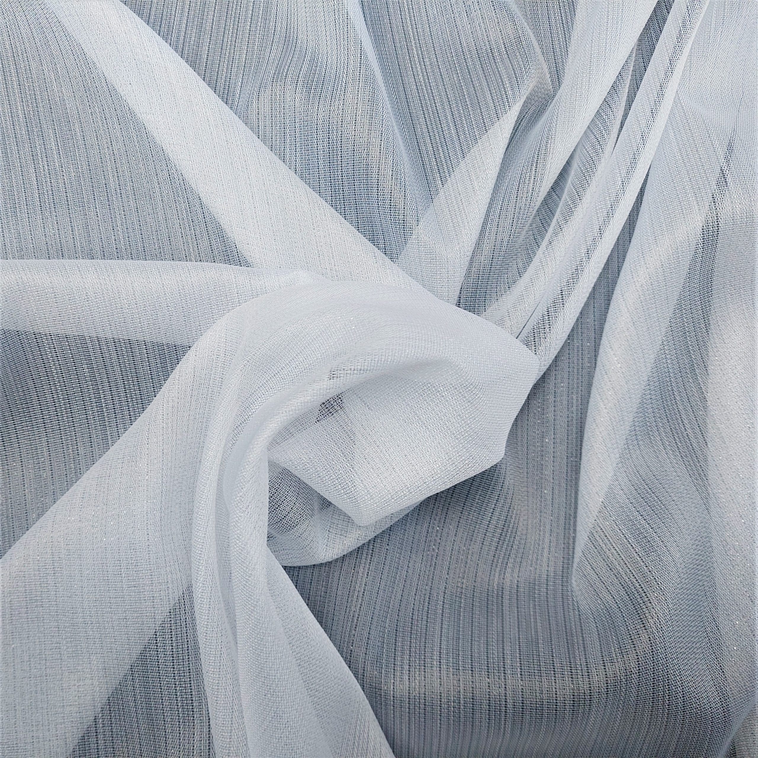 Biała tkanina tiulowa, delikatnie ułożona na szarym tle, tworzy subtelną i elegancką kompozycję.