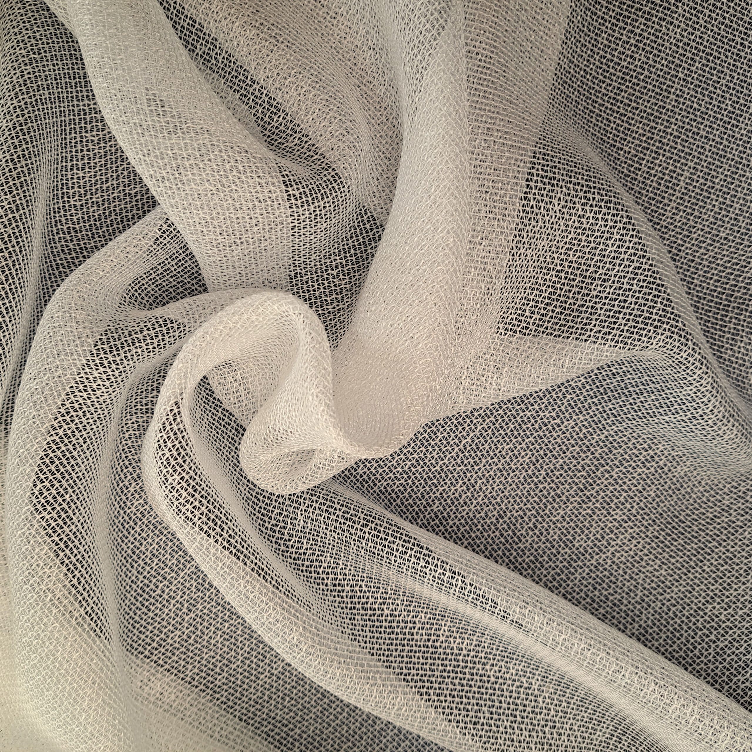 Biała, delikatna siatka z tkaniny tworząca falujące wzory, idealna na zasłony lub dekoracje wnętrz.