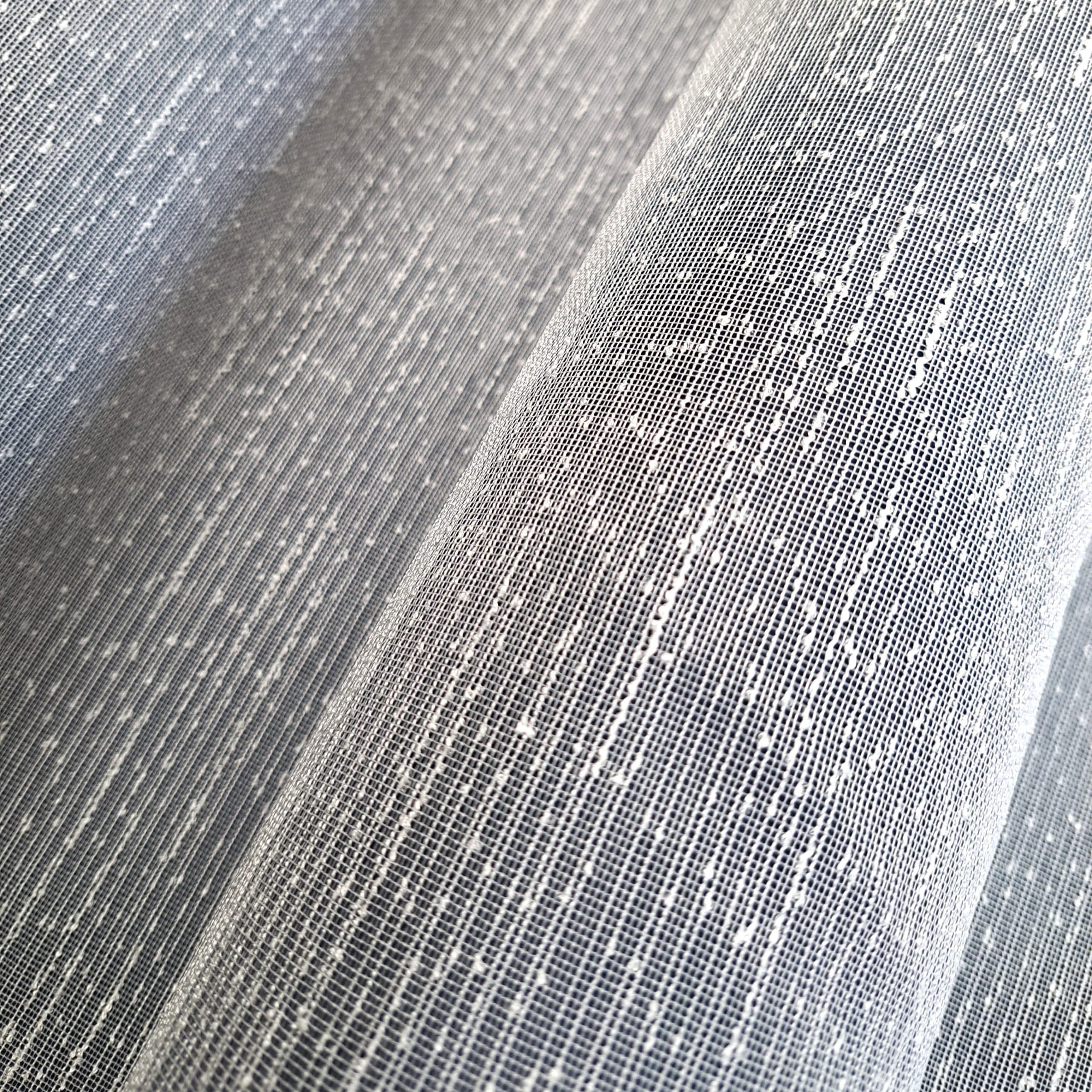 Delikatna tekstura białej tkaniny z subtelnym wzorem pionowych linii i kropek, zbliżenie.