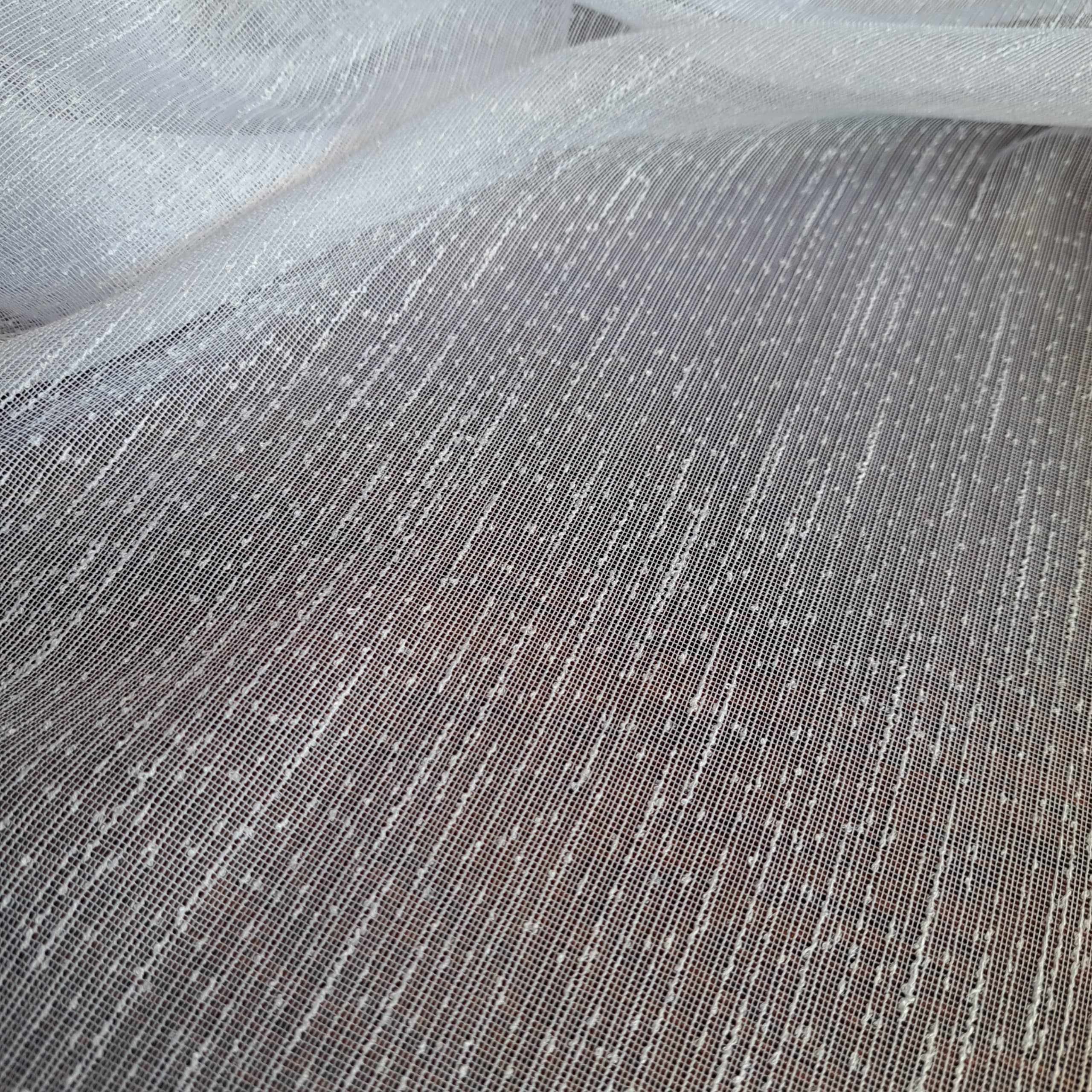 Przezroczysta biała tkanina z drobnymi przeplotami, tworząca delikatną teksturę i elegancki wygląd.