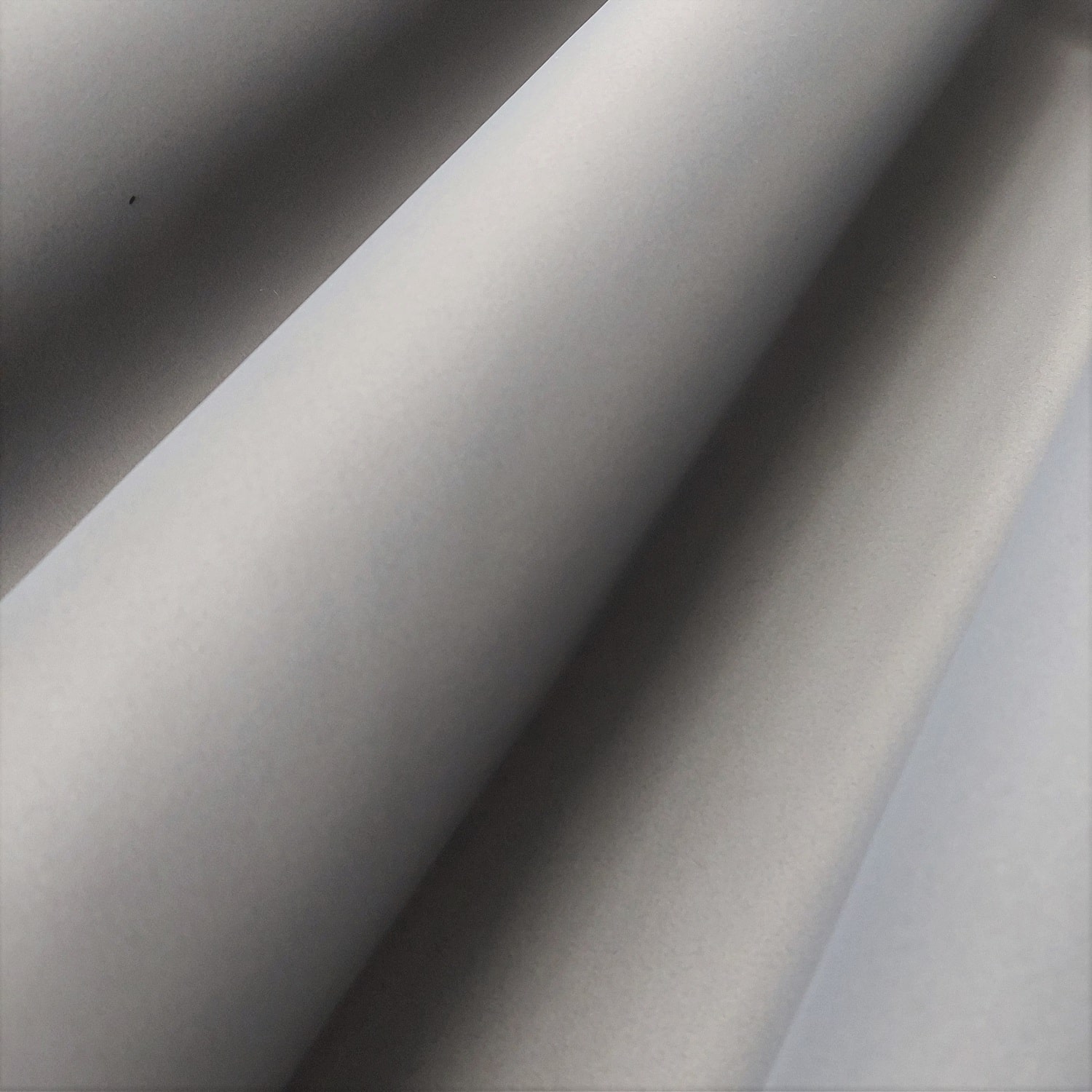 bo 115 - 1 Gładka szara powierzchnia z delikatnymi cieniami układającymi się w regularny wzór, przypominający fale.