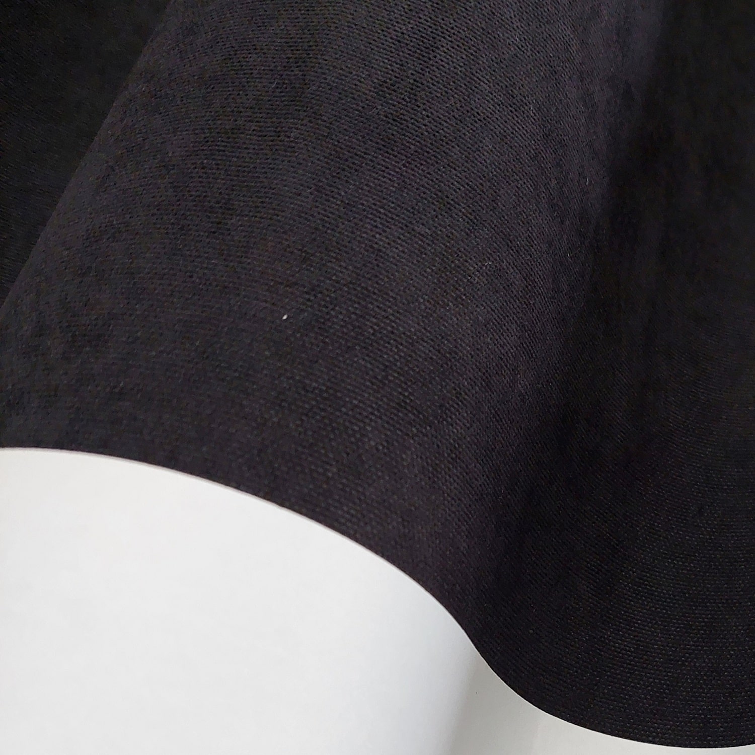 Czarny tekstylny materiał na białym tle, z bliska ukazujący strukturę i fakturę tkaniny.