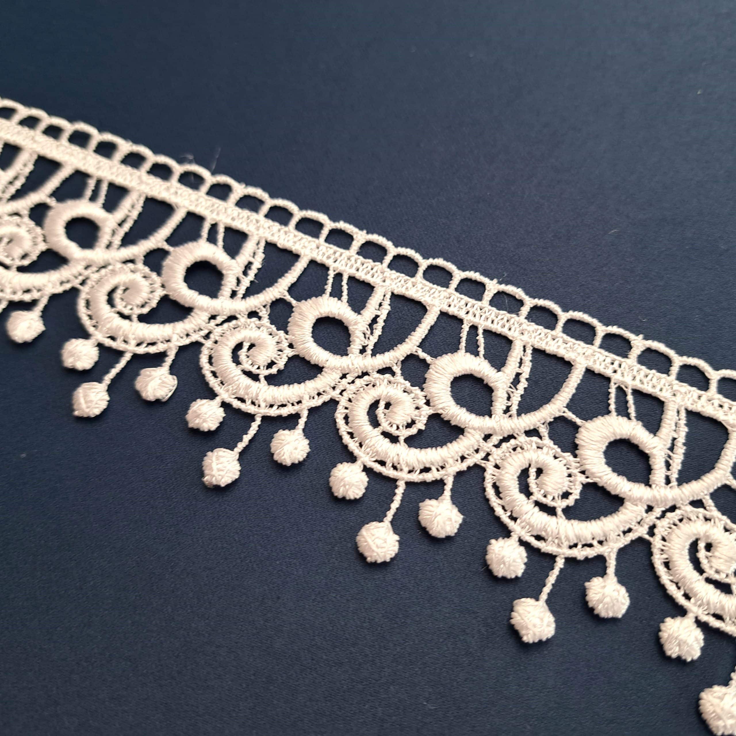 Koronkowa taśma na ciemnym tle, misterny wzór z delikatnymi detalami. Idealna do dekoracji i mody.