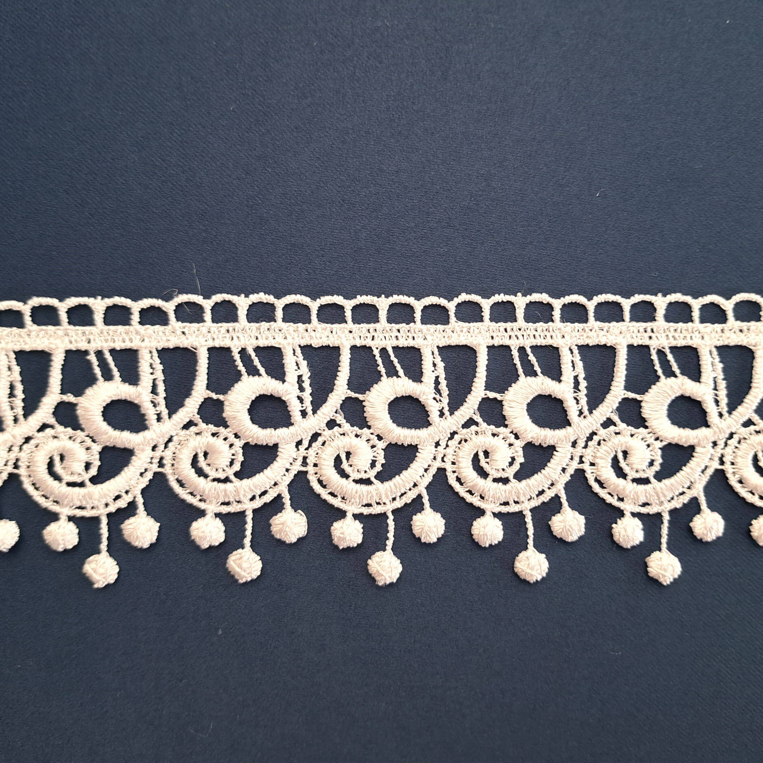 Koronka w delikatnym wzorze na ciemnym tle, idealna do dekoracji i projektów krawieckich.