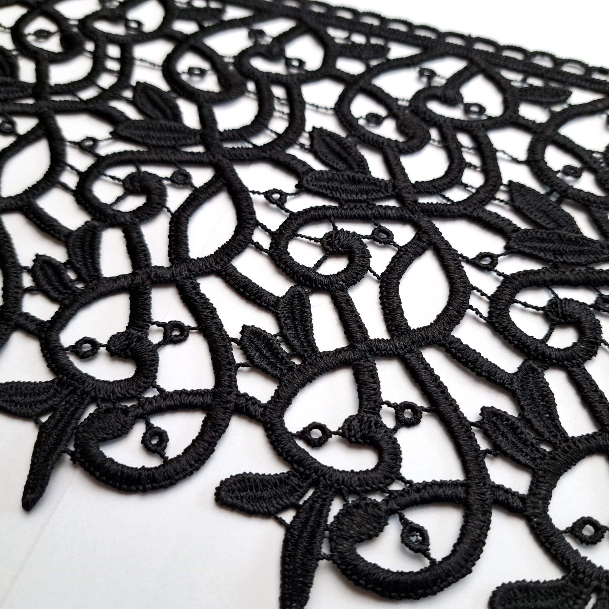 Czarna koronka z detalami w zawiły wzór, idealna na ozdobne tkaniny i dekoracje.